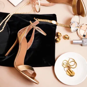 Gold metallic ankle-strap sandals styled with jewelry and clutch by Lajwanti Official.
