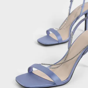 Close-up view of purple satin sandals with rhinestone crisscross straps and high heels by Lajwanti Designers.